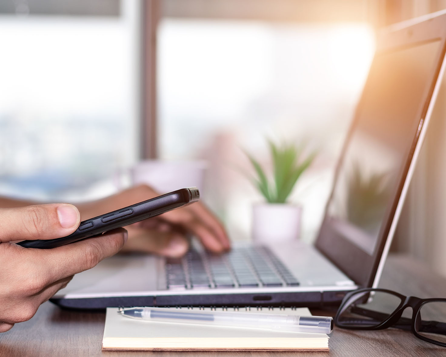 Hand holding a phone while at a computer