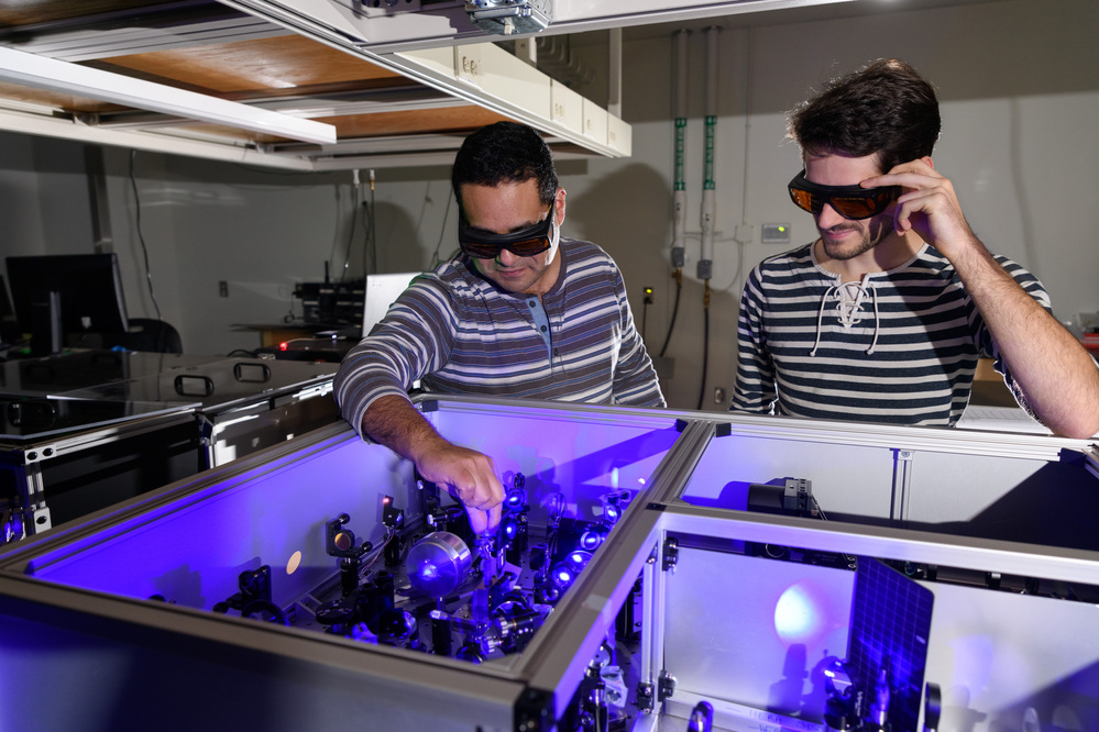 Carlos Silva (l.) in his lab at Georgia Tech with graduate research assistant Félix Thouin examining a setup to process laser light in the visible range for the testing of quantum properties in a halide organic-inorganic perovskite.