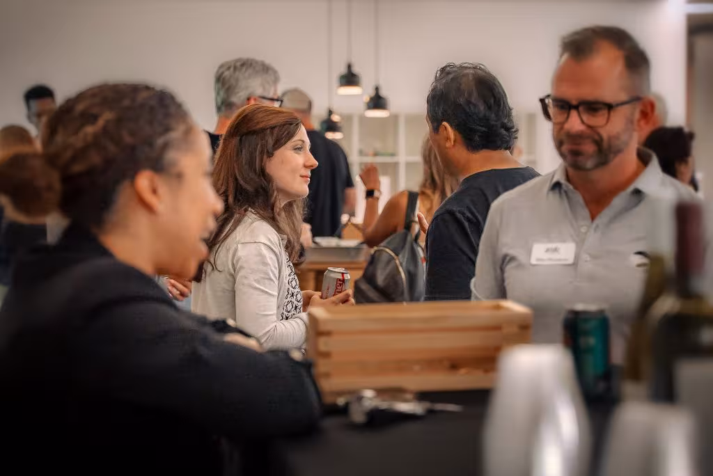 Attendees converse and network around tables during a social gathering in a modern indoor event space.