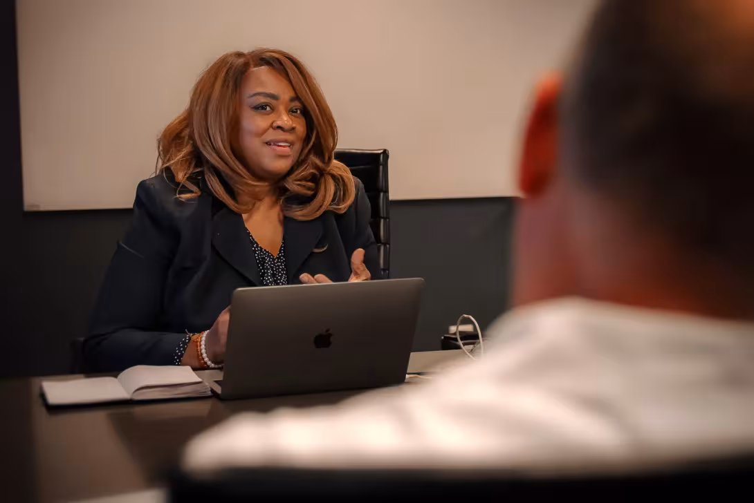 Advisor speaks with a participant across a conference table during a one-on-one coaching session.