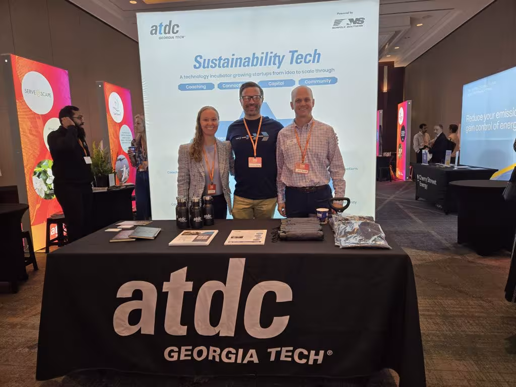 ATDC Georgia Tech team members stand behind a display table at a sustainability technology conference booth.