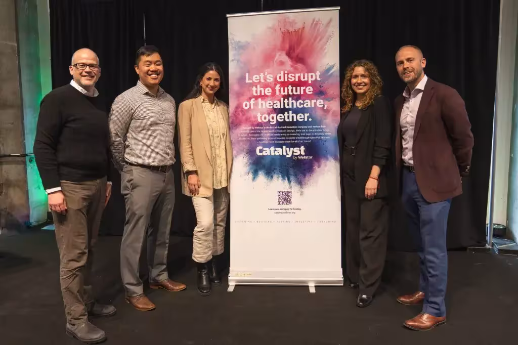 Representatives of Wellstar by Catalyst in front of their pull up banner at a HealthTech event for the healthcare technology industry.
