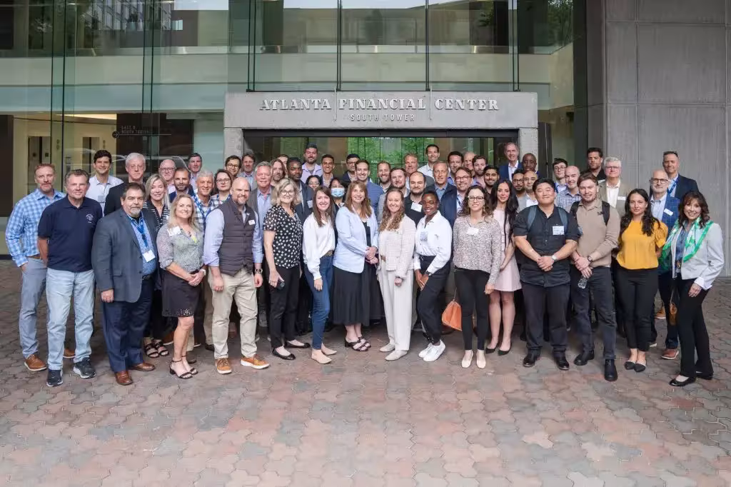 Group photo of event attendees gathered outside the Atlanta Financial Center South Tower entrance in downtown Atlanta.